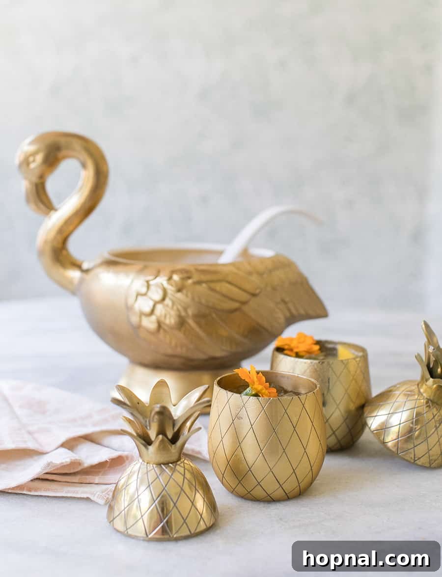 Beautifully presented punch bowl filled with tropical cocktail, surrounded by elegant glasses and tropical fruit garnishes