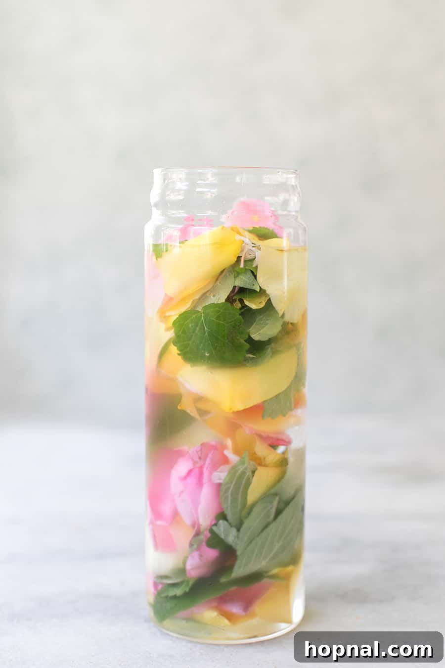 Close-up detail of a glass filled with vibrant cold brew herbal tea, showing the clarity of the liquid, the ice, and a delicate herb garnish.