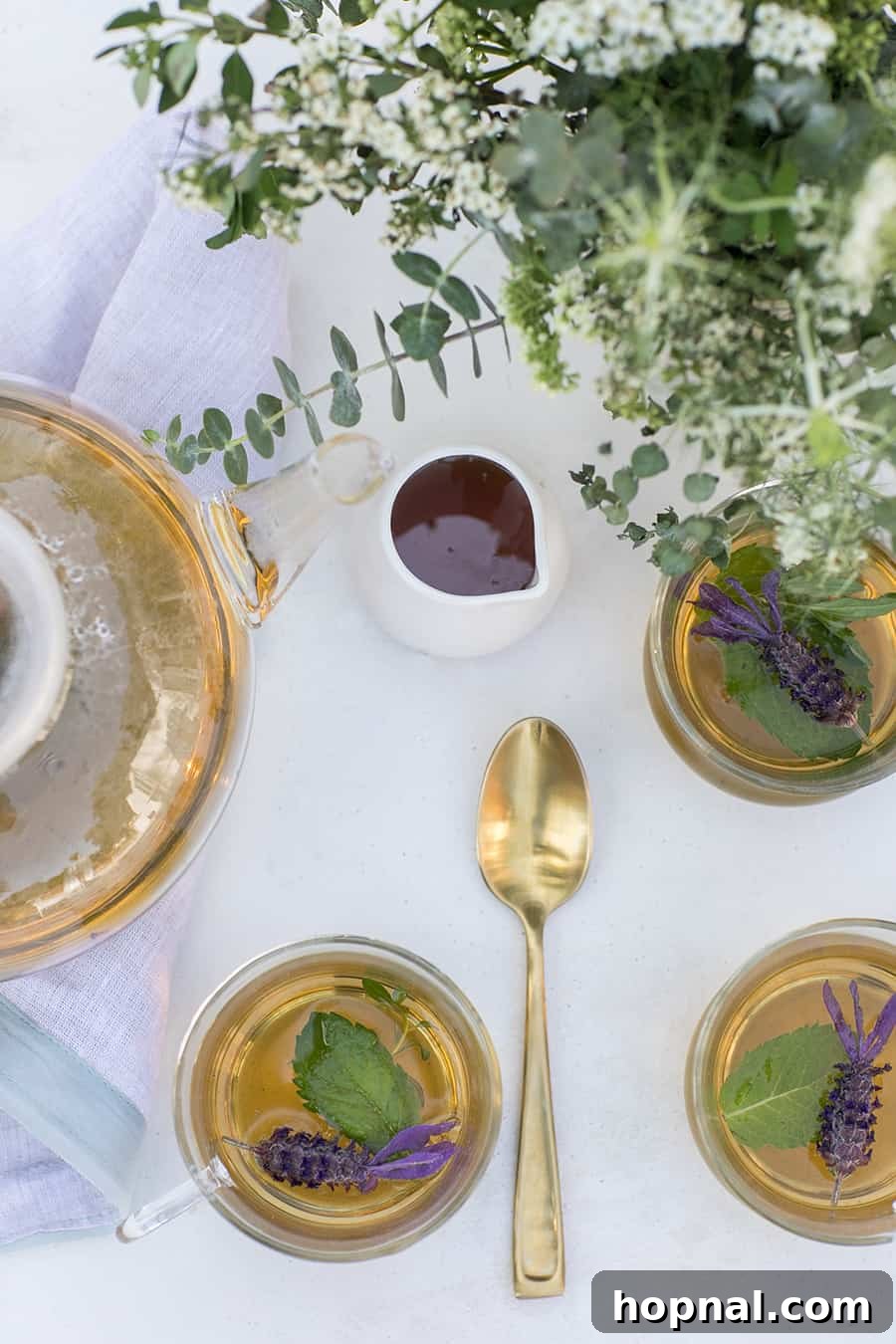 A vibrant assortment of fresh ingredients for cold brew tea: delicate rose petals, aromatic pineapple sage leaves, and bright lemon balm, carefully arranged.