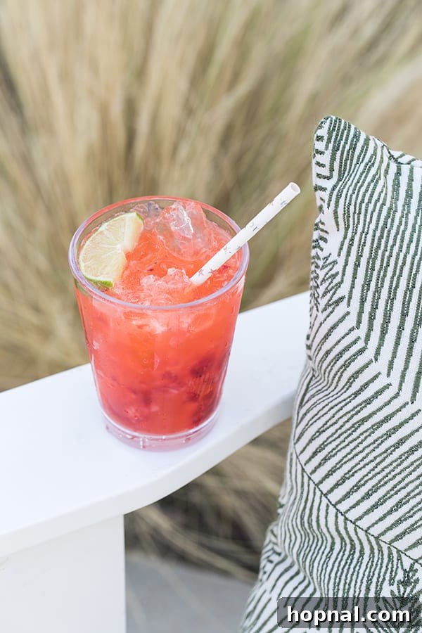 A single strawberry tequila soda in a tall glass, garnished with a lime wheel and fresh strawberry.