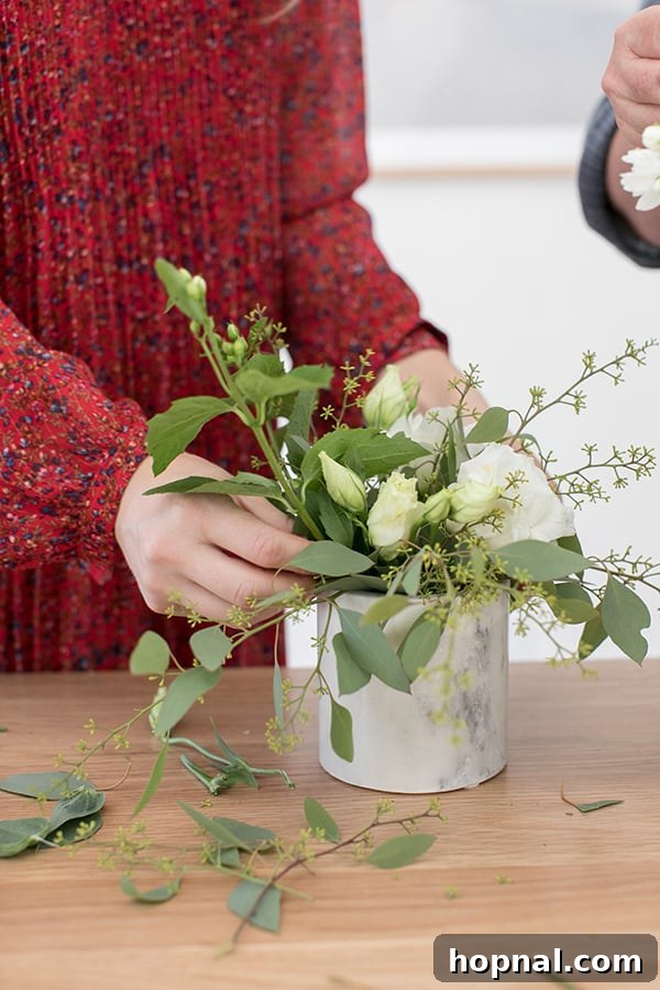 Arranging flowers in a marble vase, focusing on structural placement.