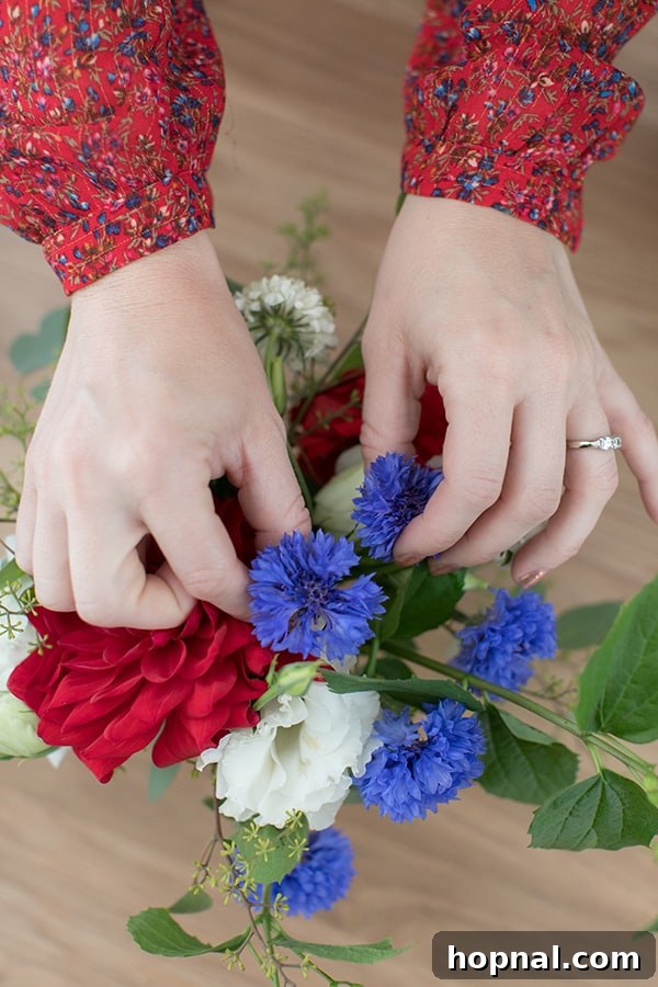 Eden Passante carefully arranging red, white, and blue flowers to achieve a balanced composition.