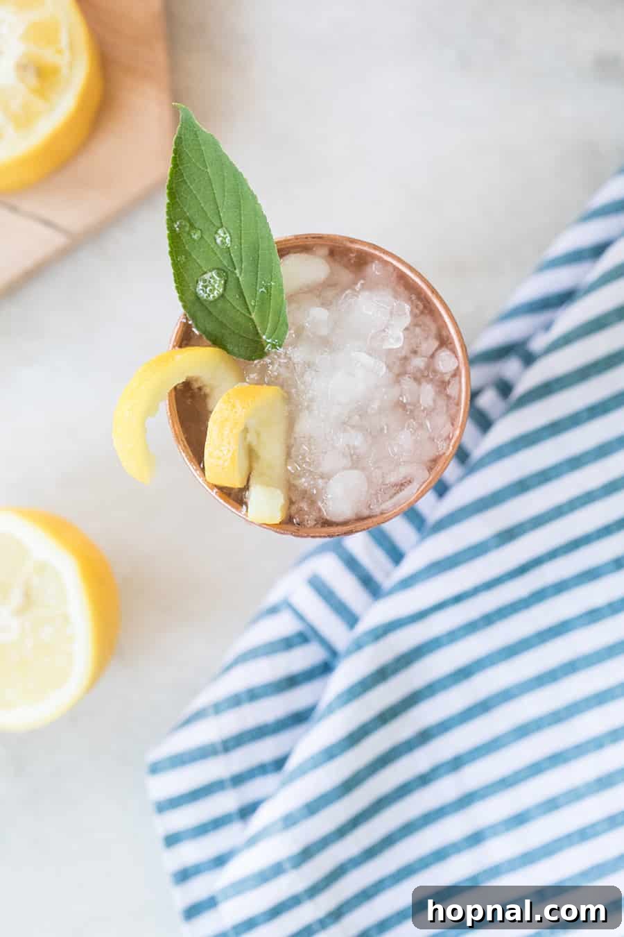 A top-down view of a vibrant Lemon and Sage Moscow Mule cocktail, showcasing its fresh garnishes.