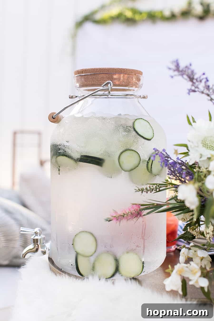 Lights, Camera, Backyard: Your Outdoor Movie Night Guide 17 A clear drink dispenser showcasing sliced cucumbers, offering a refreshing infused water option for guests.