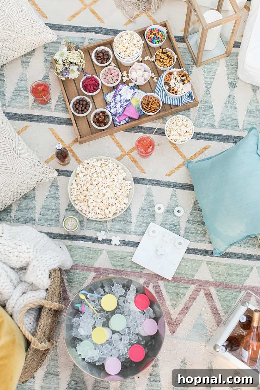 Lights, Camera, Backyard: Your Outdoor Movie Night Guide 6 An overhead view of an outdoor movie night scene, featuring popcorn, various pillows, board games, and a tray laden with an assortment of candies.