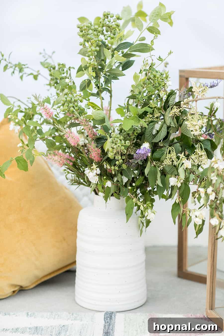 Lights, Camera, Backyard: Your Outdoor Movie Night Guide 9 A white vase filled with vibrant flowers sits next to bright yellow pillows, enhancing the outdoor decor with color and comfort.