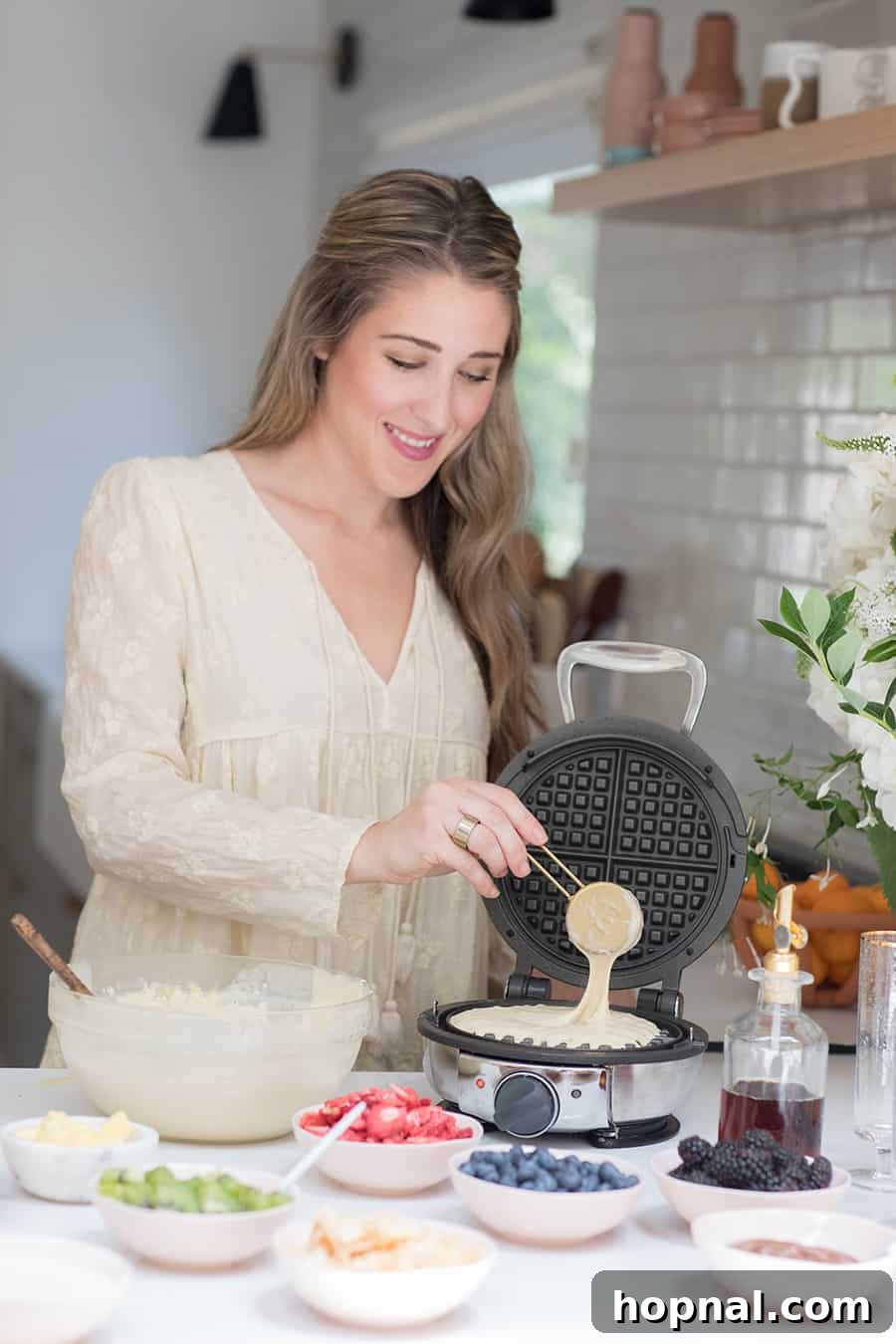 Eden Passante making homemade waffles in a round waffle maker.