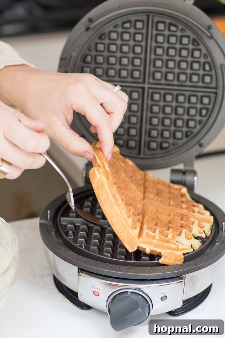 pulling out a cooked homemade waffle recipe from a waffle maker.