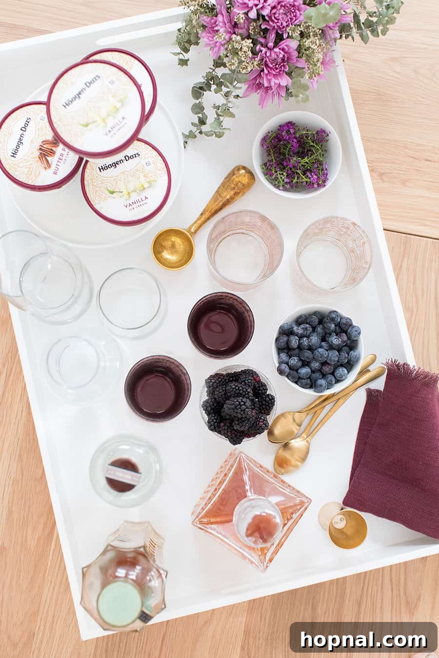 ice cream sundae bar on a white tray with berries and silverware 