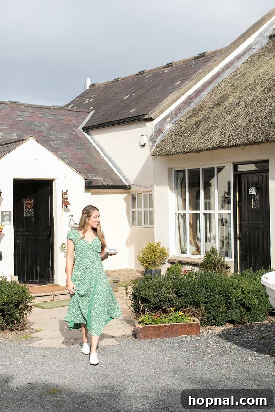 Master the Art of Irish Soda Bread 3 Eden Passante standing in front of a rustic, charming thatched-roof cottage in Northern Ireland.