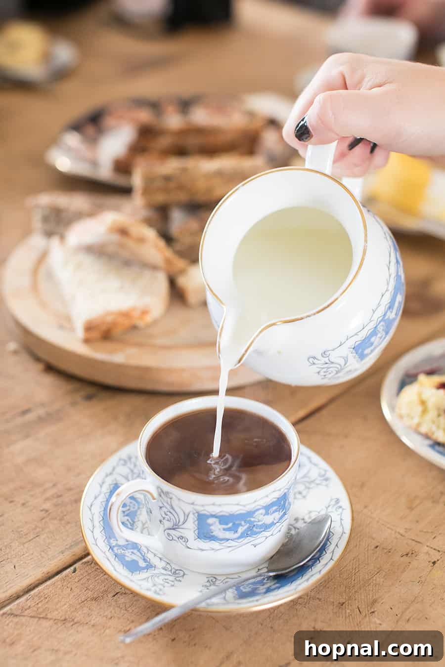 Master the Art of Irish Soda Bread 10 Pouring rich cream into a delicate tea cup, signifying a cozy break with warm beverages.