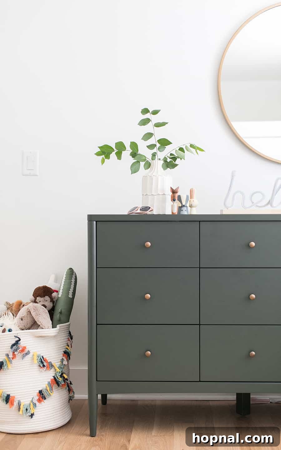 Boys room with an olive green dresser and a gold mirror. 