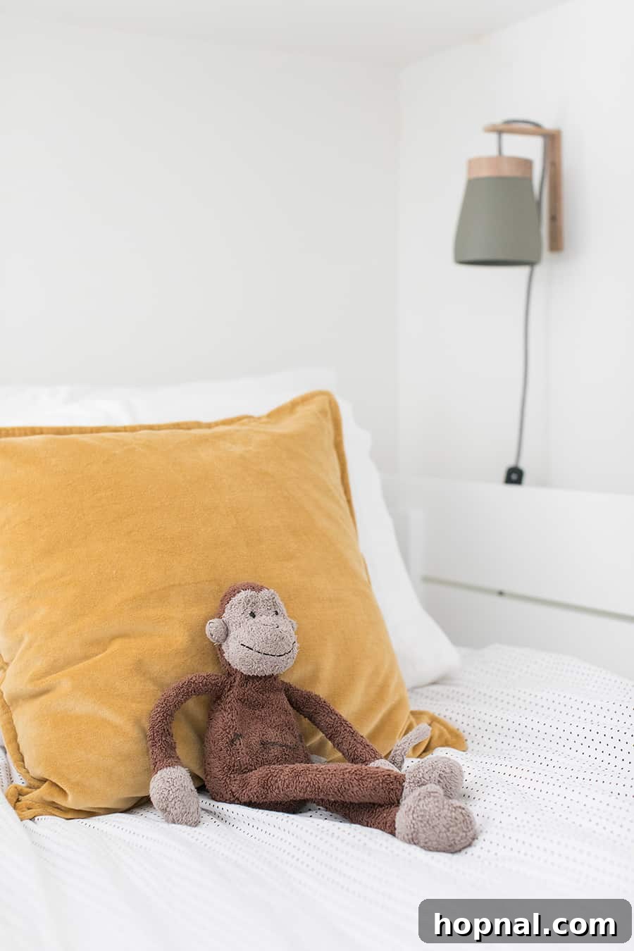 Kids bedroom with velvet yellow pillows and a stuffed monkey.