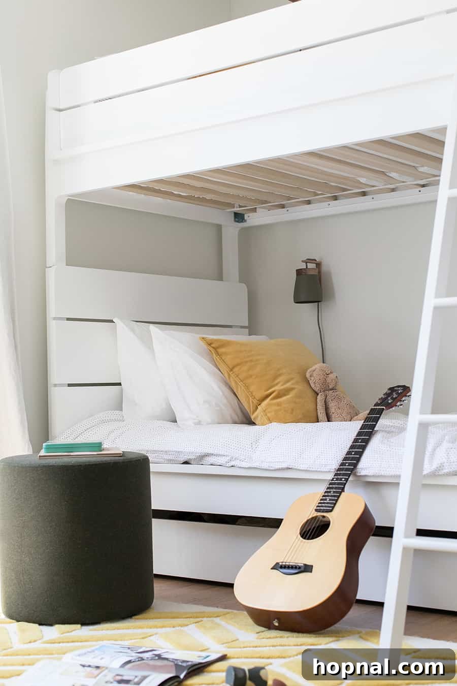 White bunkbeds in a boys room with yellow pillow, white bedding and a guitar.