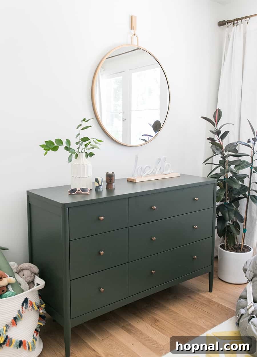 Olive green dresser with plant and a gold mirror.