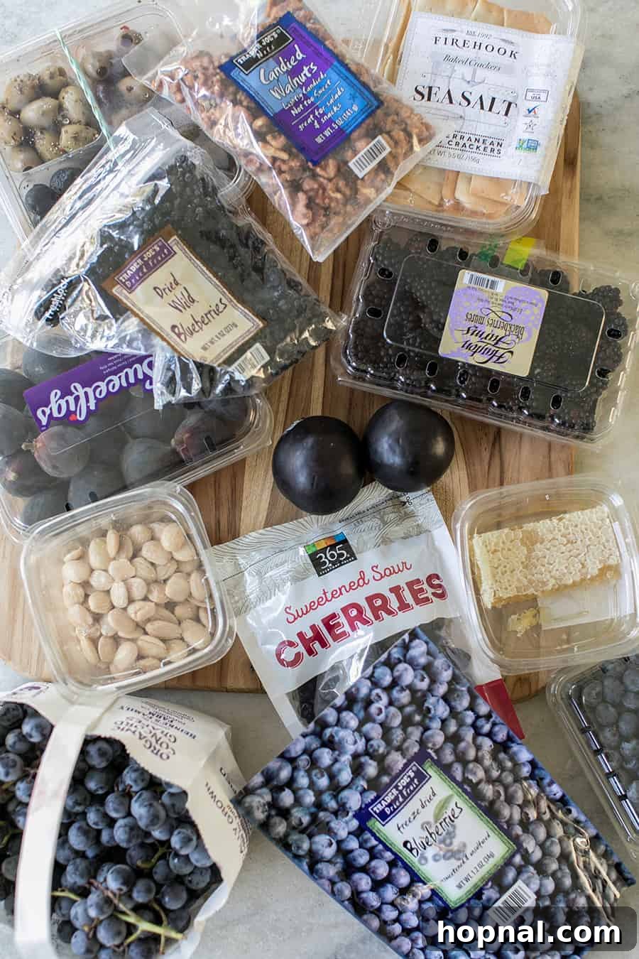 Berries, nuts, honey, and grapes arranged on a board, ready for a meat and cheese platter.