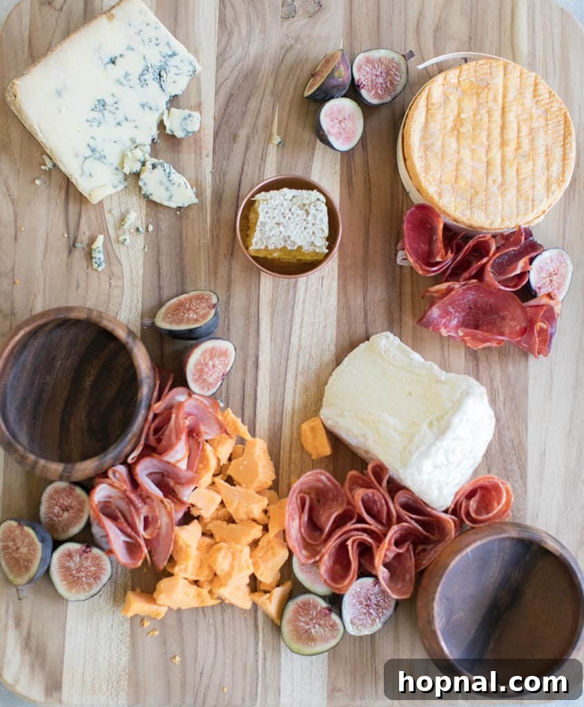 Assembling a Halloween appetizer platter, showing the addition of meats and fruits.