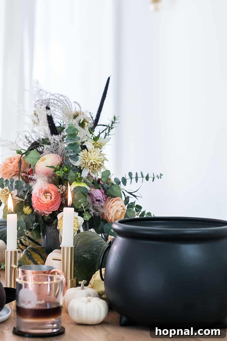 Cauldron filled with steaming curried butternut squash soup on an elegantly decorated Halloween dinner table.
