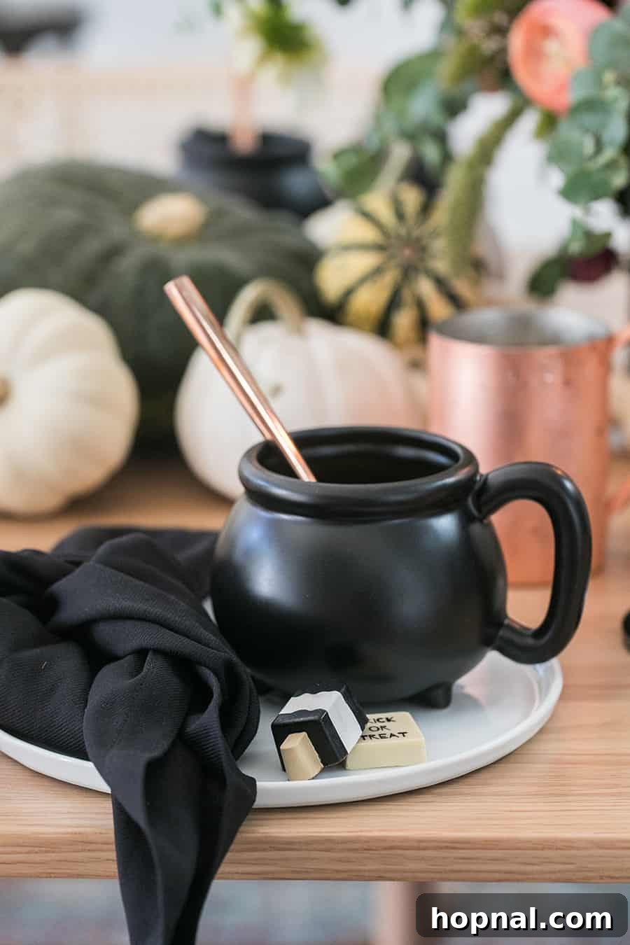 Close-up shot of a mini mug cauldron, perfectly sized for individual soup servings, accompanied by small chocolates and a black napkin.