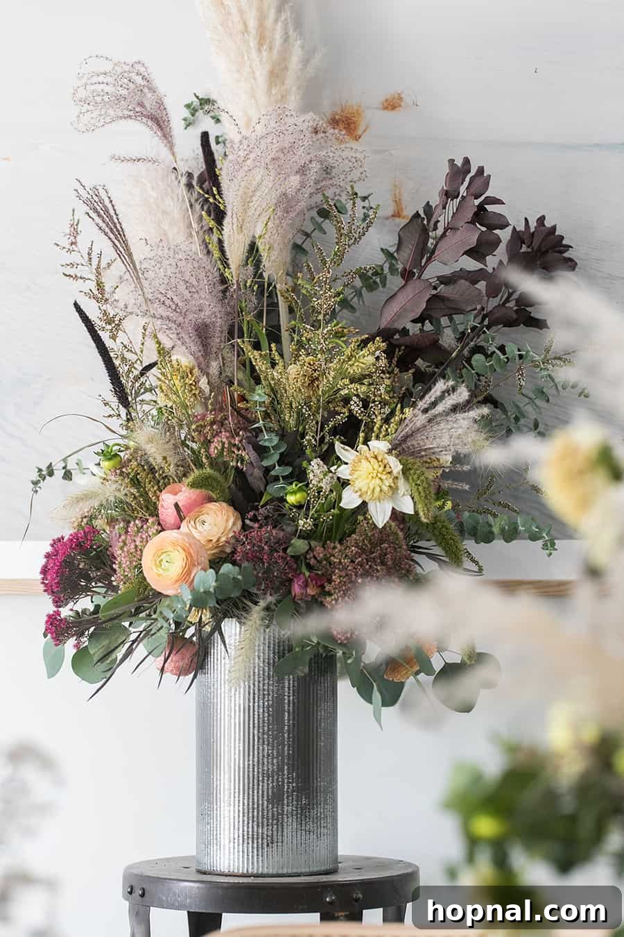 Halloween Dinner Ideas Decorations showcasing a beautiful fall floral arrangement in a tall metal vase, set on a dark table.