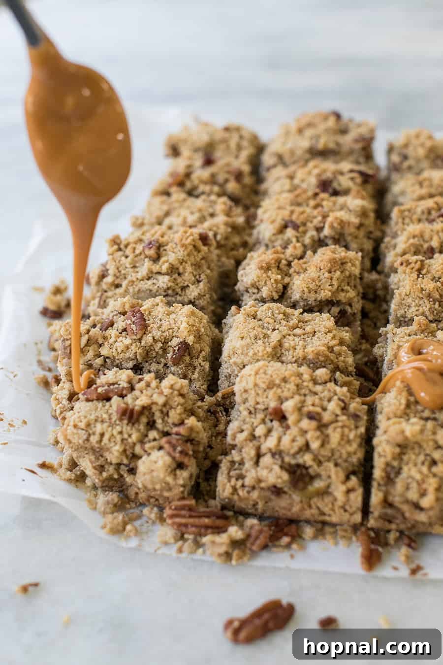 Ultimate Caramel Apple Crumble Bars 4 Hand drizzling warm caramel sauce over a pan of freshly baked apple crumble bars.