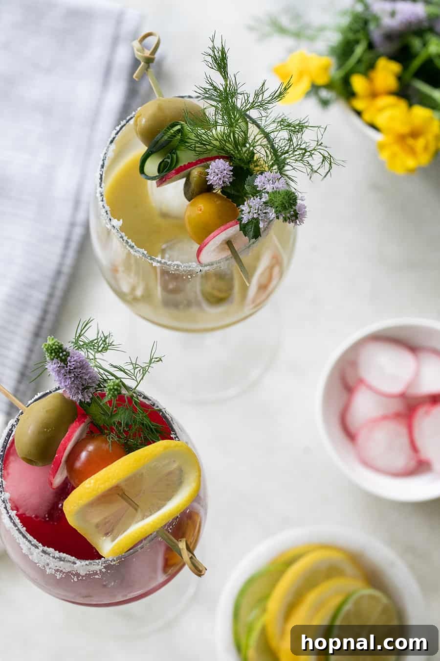 Craft Your Ultimate Home Bloody Mary Bar 2 A beautifully garnished Bloody Mary cocktail in a wine glass, surrounded by fresh olives and flowers.