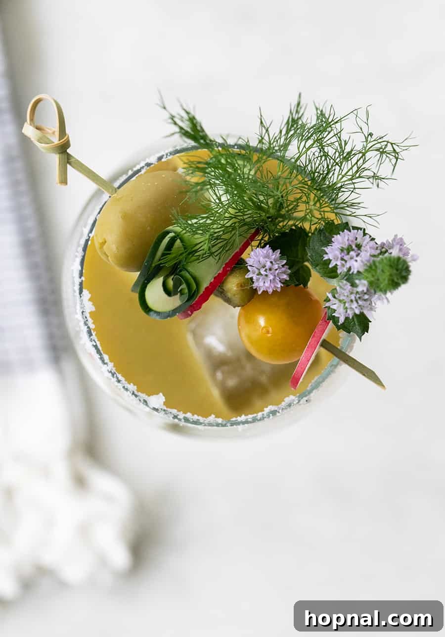Craft Your Ultimate Home Bloody Mary Bar 14 Overhead shot of a vibrant tomatillo Bloody Mary, artfully garnished with cucumber, olives, and cherry tomatoes.