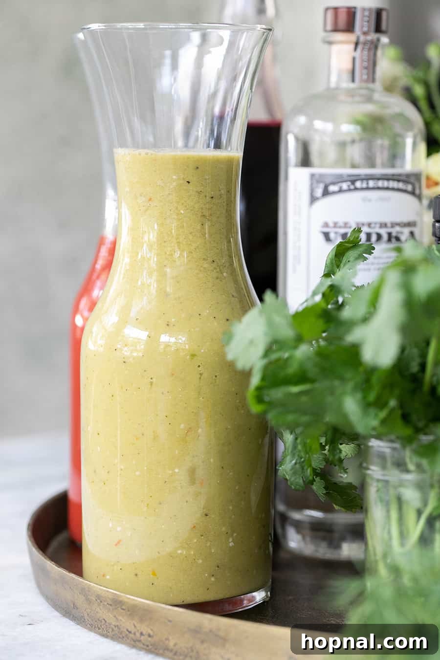 Craft Your Ultimate Home Bloody Mary Bar 5 A tall glass filled with vibrant Tomatillo Bloody Mary mix, ready for custom garnishing.