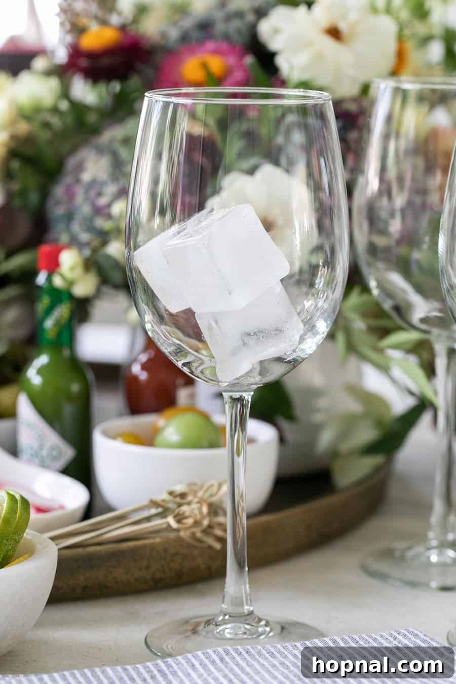 Craft Your Ultimate Home Bloody Mary Bar 10 Small, elegant ice cubes nestled in a wine glass, ready for a Bloody Mary.