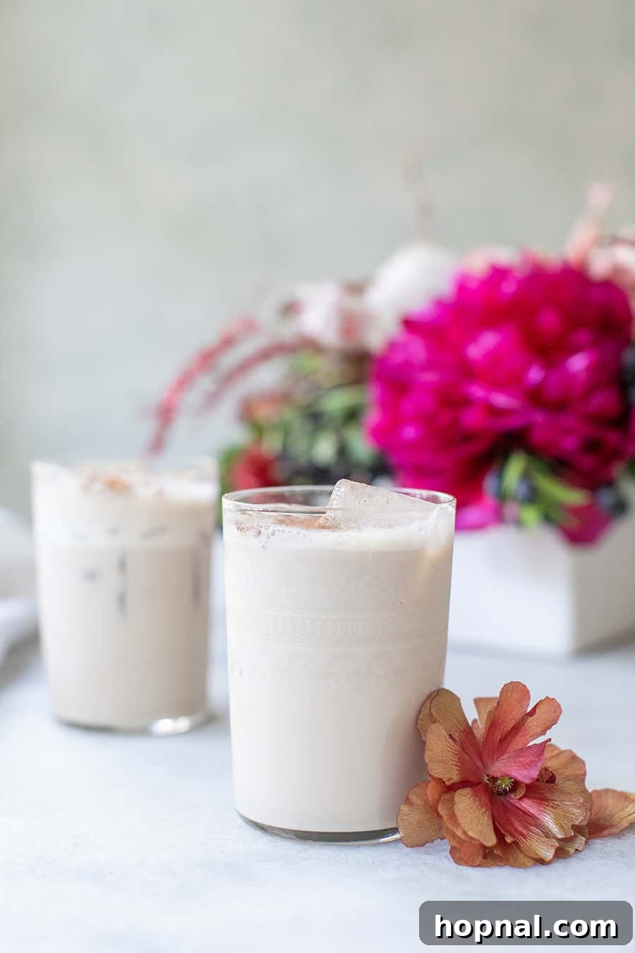 Palermo Passion 4 Two Sicilian Kiss cocktails, beautifully presented in elegant glasses with delicate pink flowers, highlighting the luxurious and inviting nature of the drink.