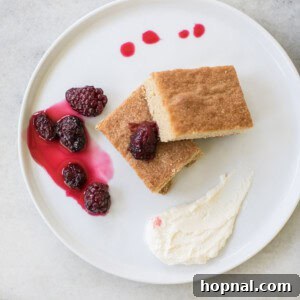 A beautifully baked brown sugar cake with cream and blackberries, ready to be served.