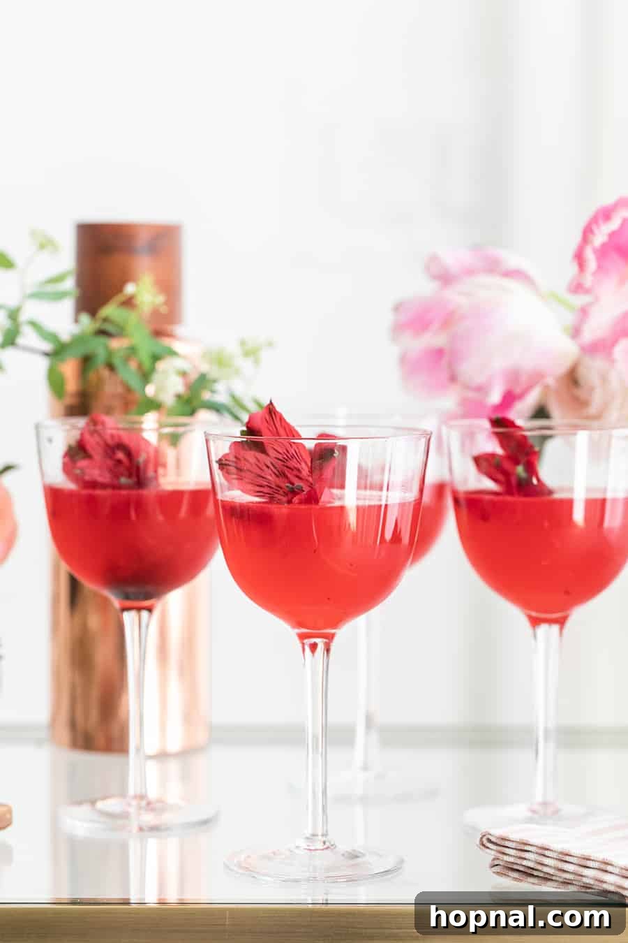 The Gin Blossom Room 3 Beautiful pink cocktails garnished with flowers.
