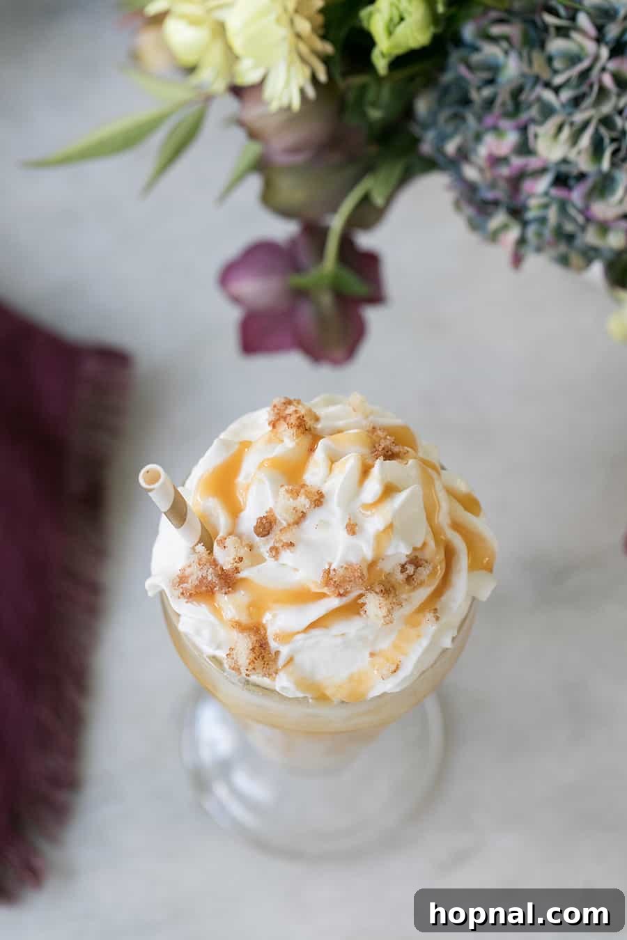 Coffee milkshake with a generous topping of whipped cream and a drizzle of caramel sauce.