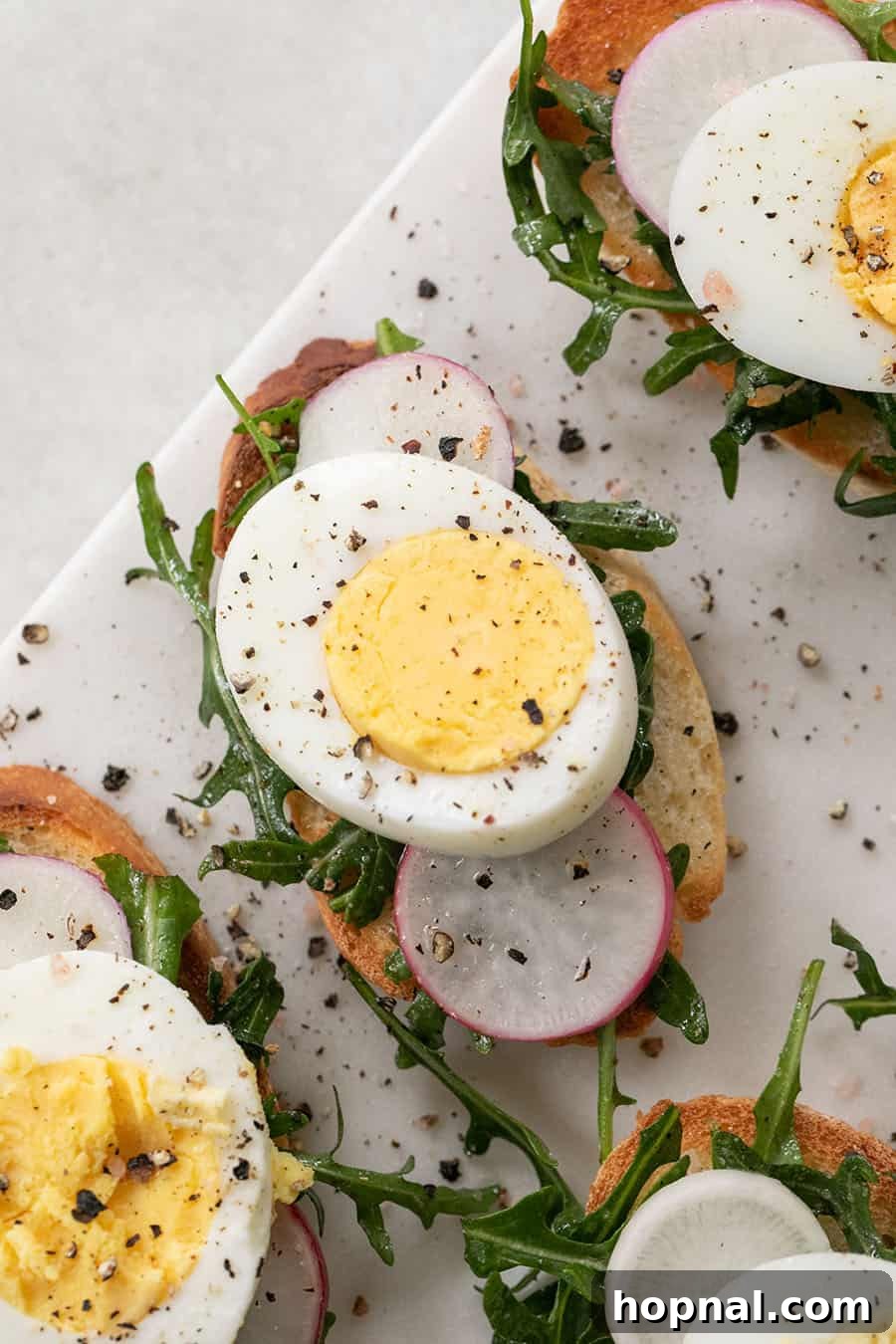 Gourmet Hard-Boiled Egg Crostini Bites 3 hard boiled egg, sliced on a crostini with salt and pepper and radish. A single crostini prepared and ready to be served.