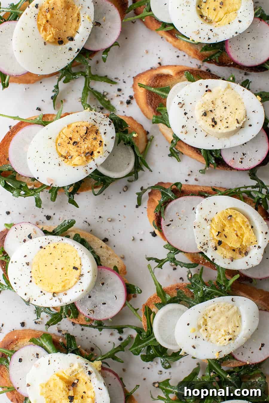 Gourmet Hard-Boiled Egg Crostini Bites 5 Crostini recipe with hard boiled eggs, radish, arugula and salt and pepper. A platter of finished crostini, ready for serving.