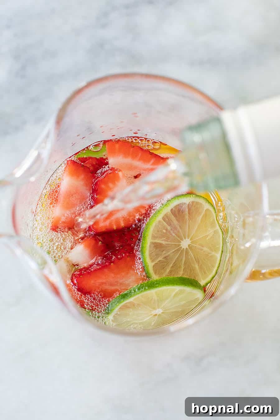 White wine sangria with vodka is poured into a glass pitcher for white sangria.