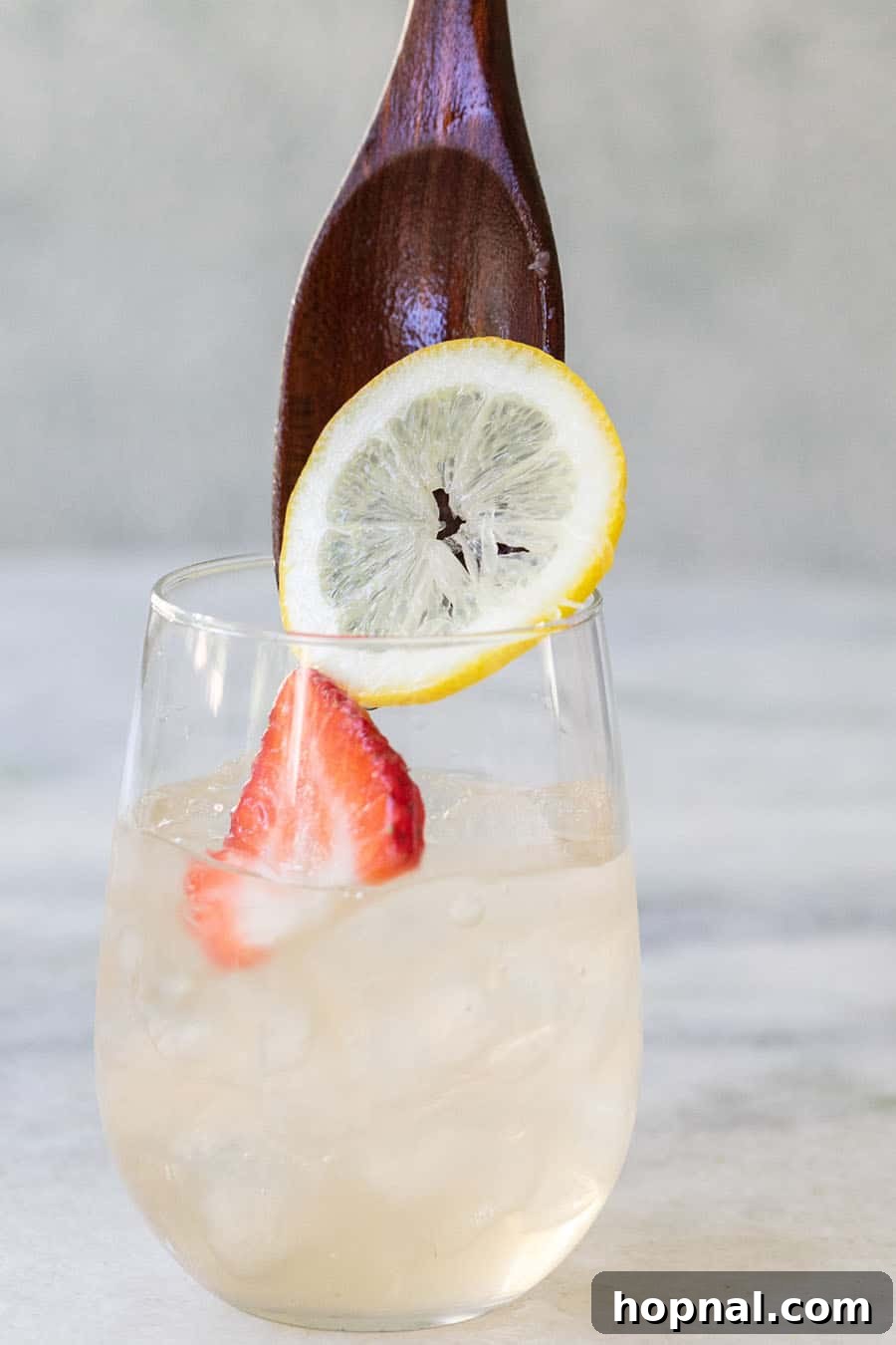 Wooden spoon dropping in ingredients for a white wine sangria.