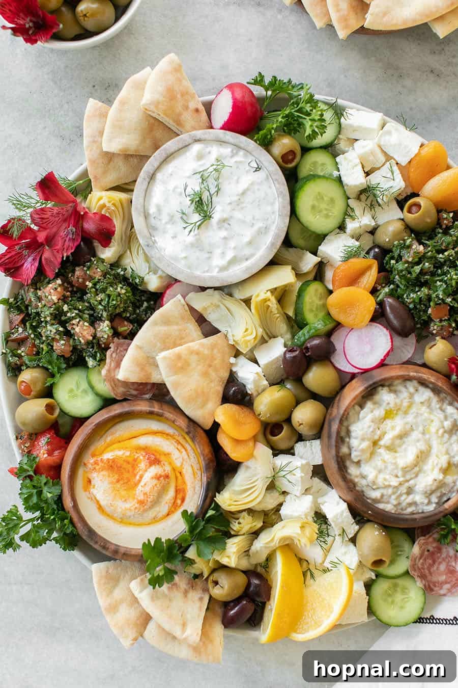 Vibrant Greek Mezze Platter featuring creamy yogurt dip, fresh olives, crisp radish, and warm bread slices, artfully arranged for sharing.