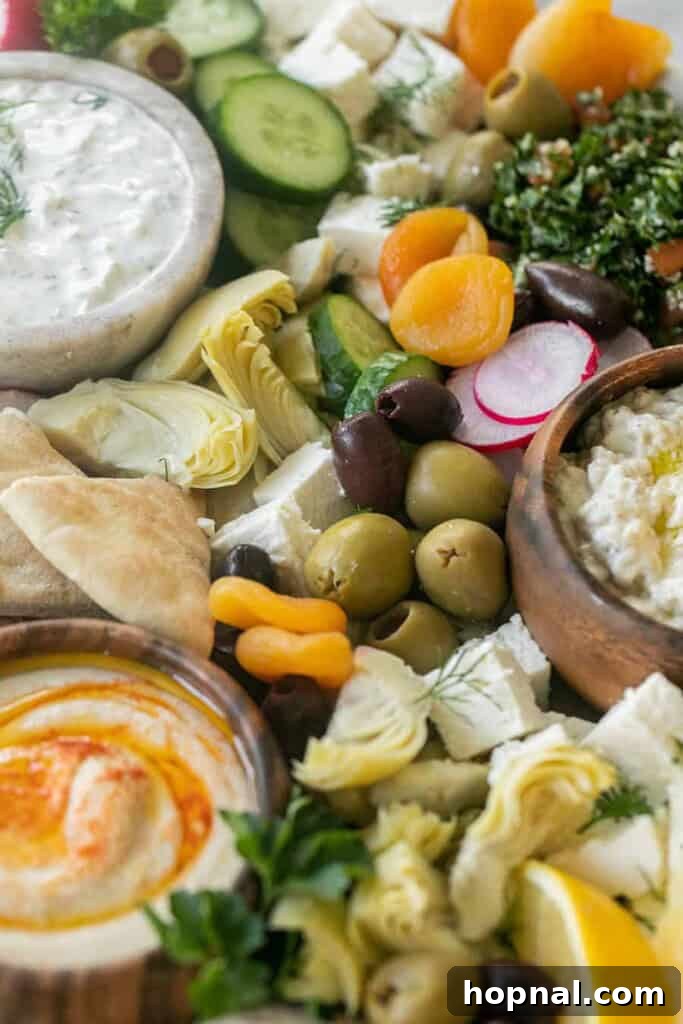 A generously filled Greek mezze platter with an abundance of olives, various cheeses, fresh pita bread, and an assortment of creamy dips.