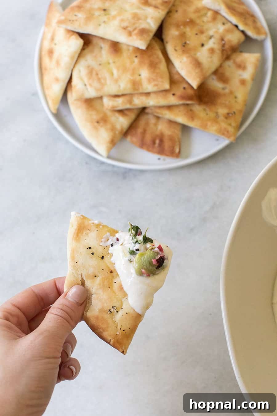 A section of warm, fluffy pita bread laden with creamy tahini yogurt dip and its vibrant lima bean topping, ready to be enjoyed.