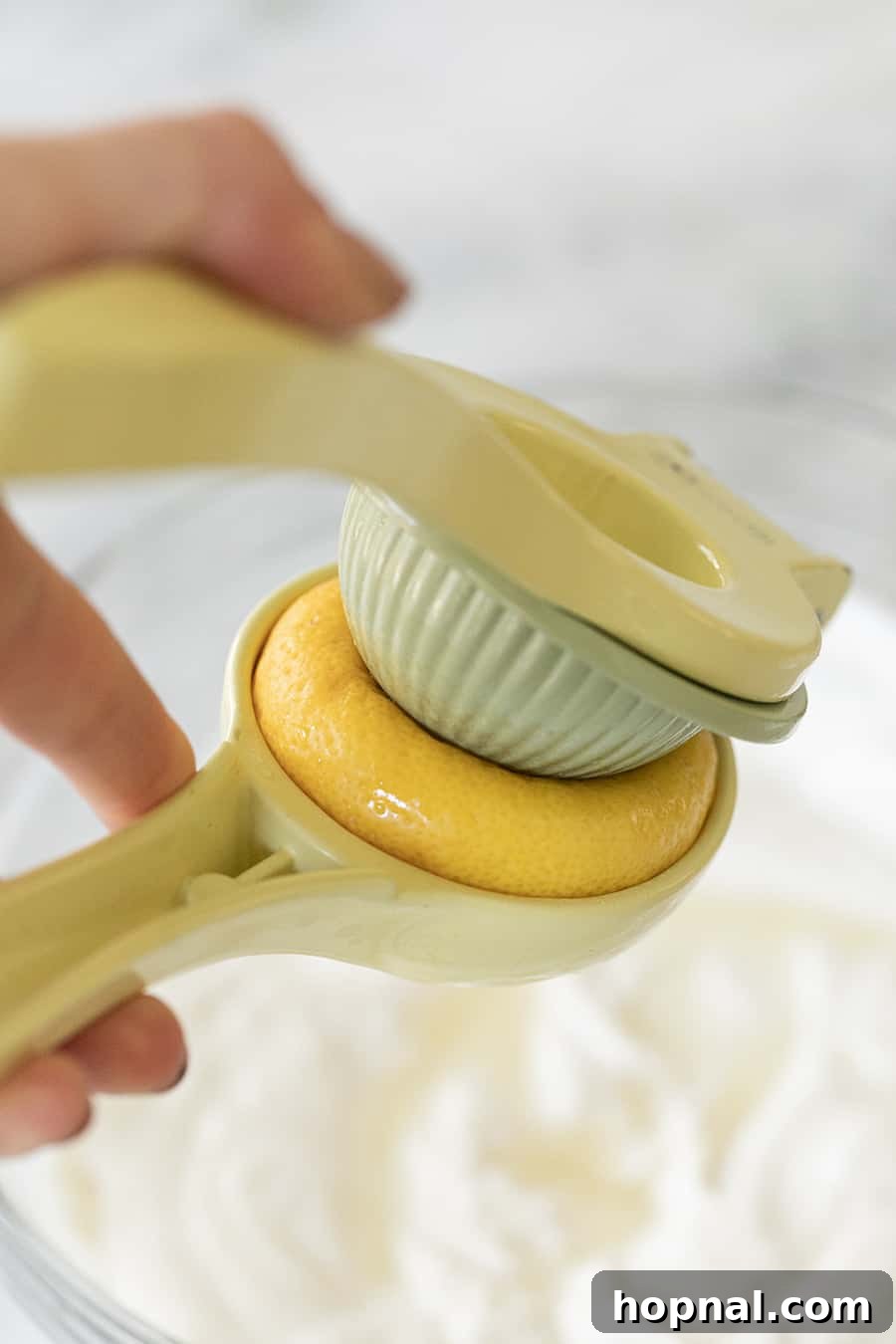 A fresh lemon being juiced with a citrus squeezer, with bright lemon zest visible, adding essential tanginess to the yogurt dip.