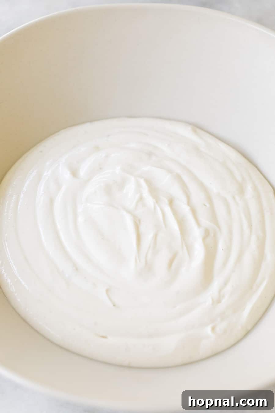 A bowl of freshly mixed, smooth and creamy yogurt tahini dip, perfectly seasoned and ready for topping.