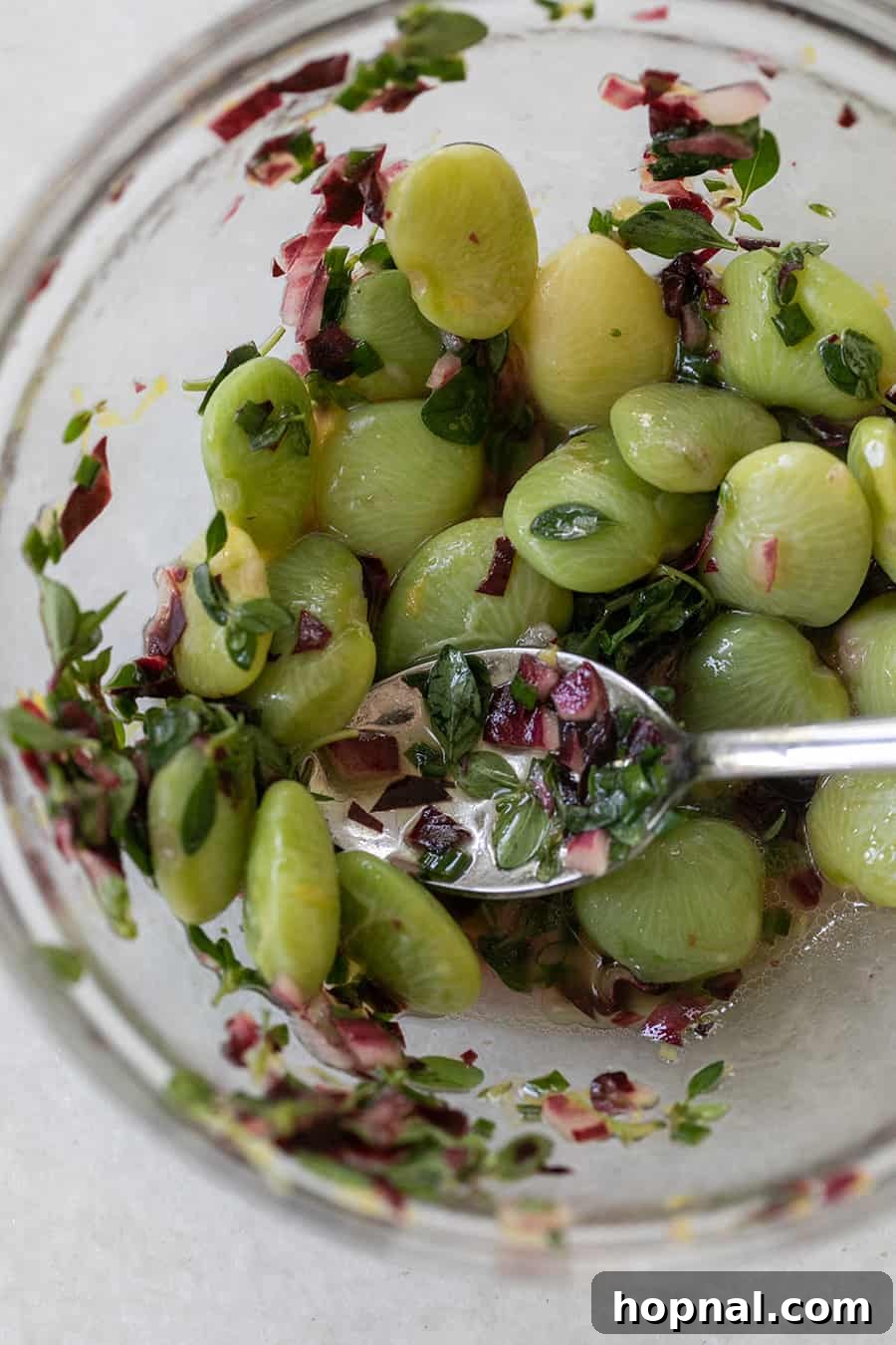 A vibrant mix of cooked lima beans, thinly sliced green onions, and fresh thyme leaves in a bowl, tossed with olive oil – the base for the flavorful dip topping.