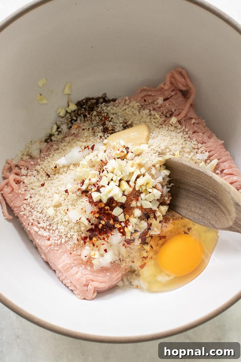 Savory Turkey Meatball Delights 4 Bowl with ground turkey and ingredients, being stirred with a wooden spoon.