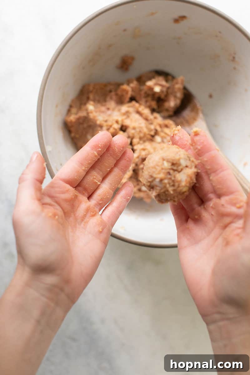 Savory Turkey Meatball Delights 5 Hands shaping a raw turkey meatball mixture into a perfect ball.