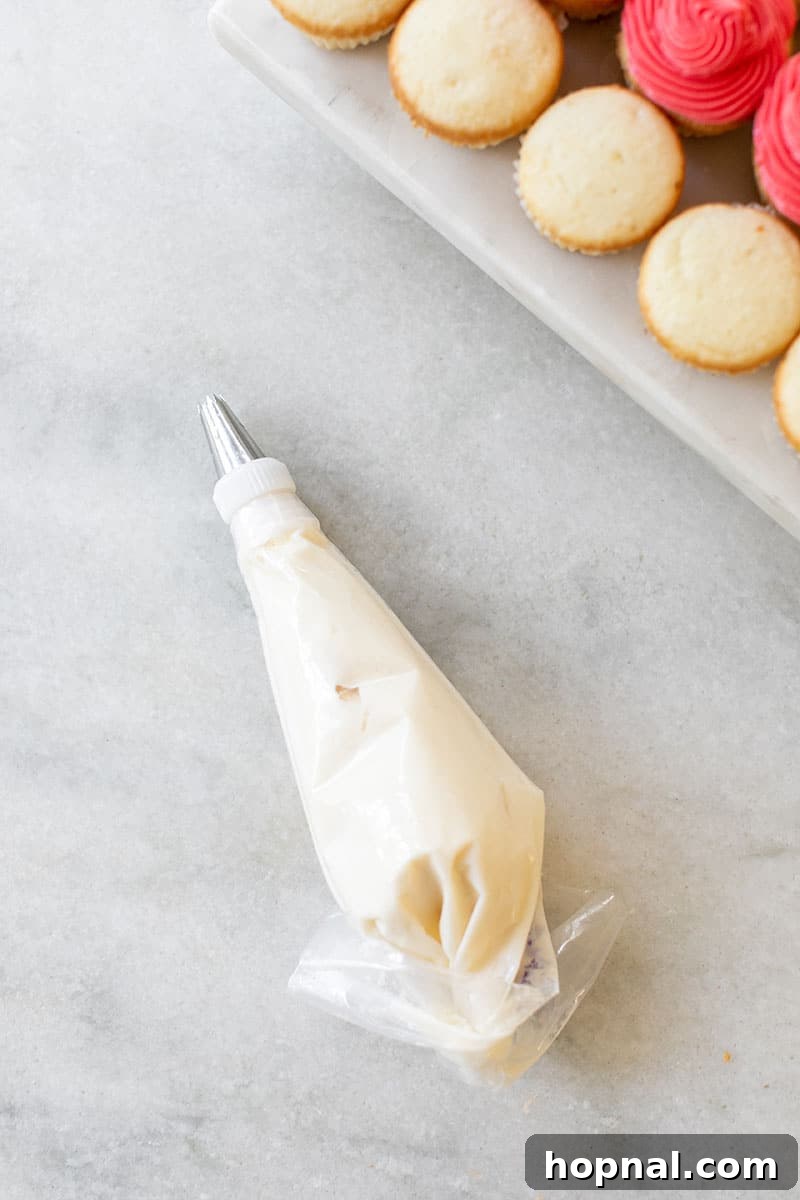 Creamy, colorful frosting prepared in piping bags on a marble surface