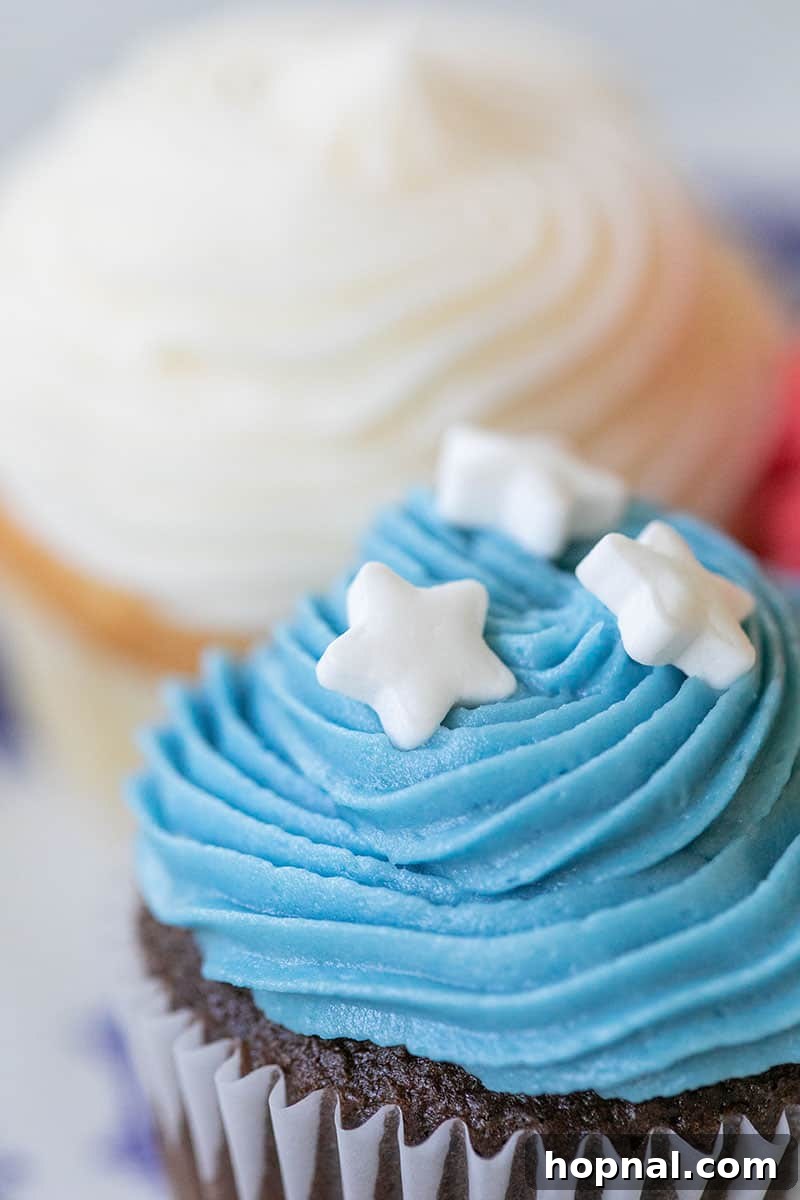 A single mini cupcake with blue frosting and white star sprinkles