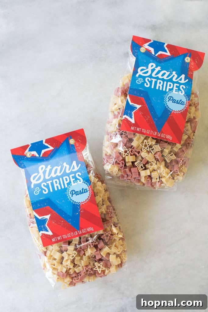 A vibrant and patriotic pasta salad recipe, adorned with star-shaped pasta and striped vegetables, perfect for a 4th of July celebration.