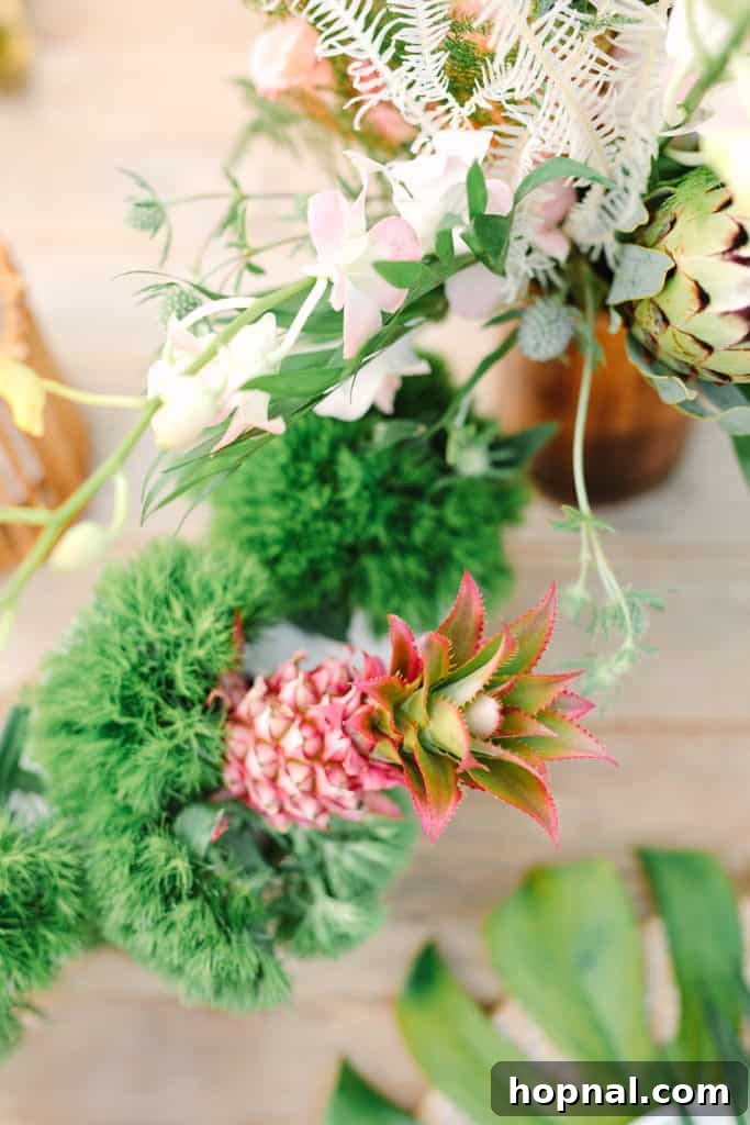 A charming mini pink pineapple artfully displayed with lush tropical flowers, creating an elegant decor piece.