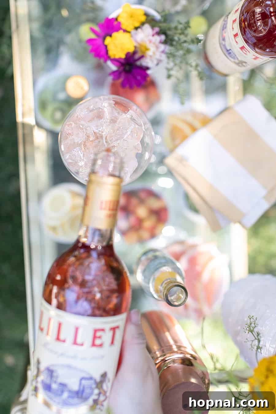 Craft Your Own Spritzer Bar 6 A hand pouring Lillet into a wine glass filled with ice, illustrating the spritzer-making process.
